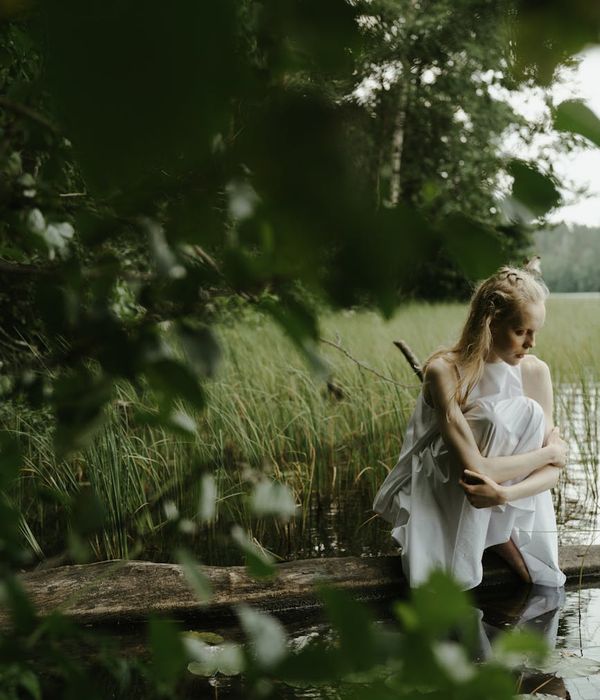 Woman sitting peacefully with eyes closed in a calm environment.
